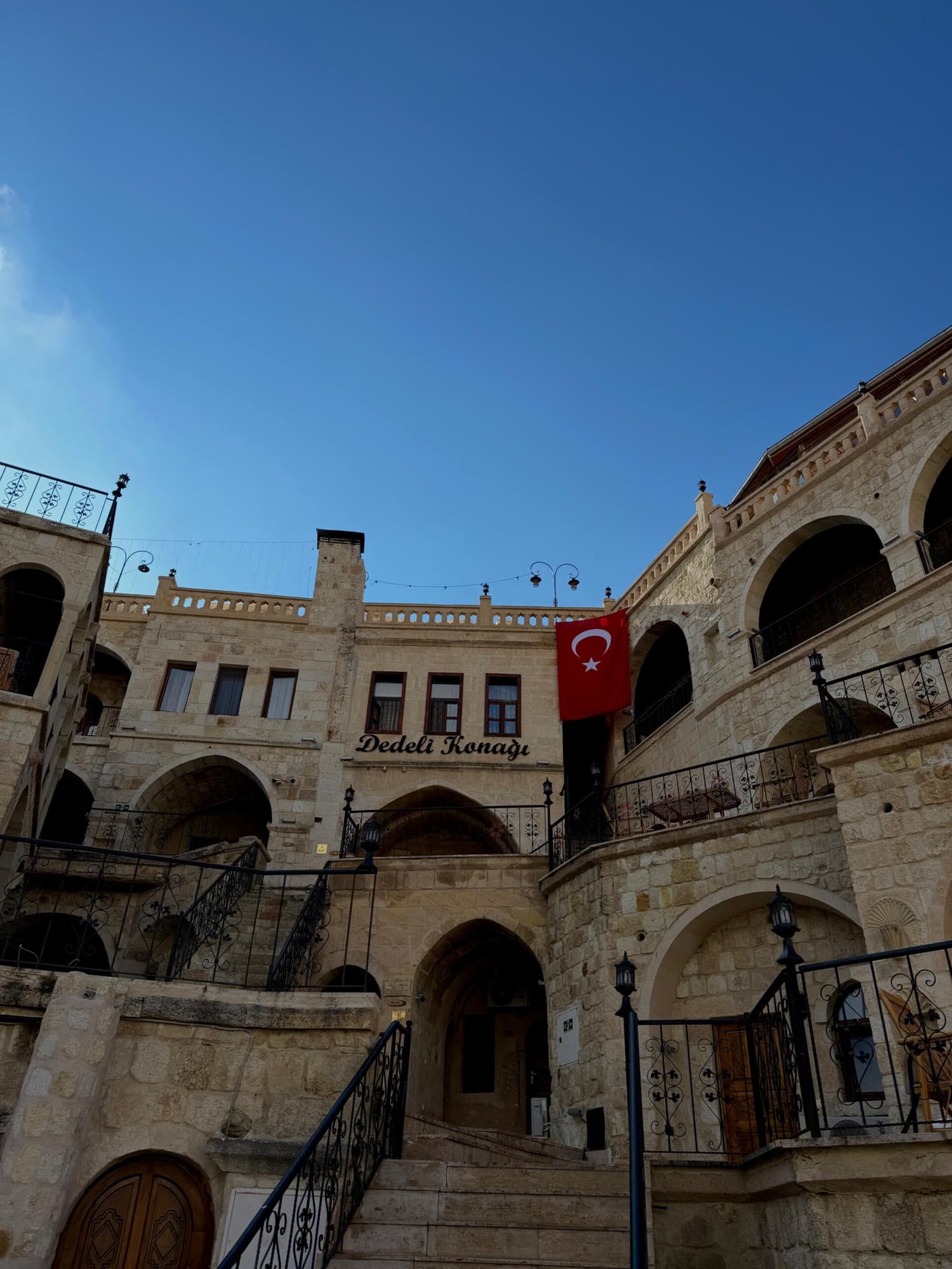 Gündüz mavi gökyüzü altında kemerli avlu ve merdivenler